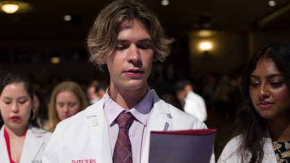 A student reads from the program during the White Coat Ceremony